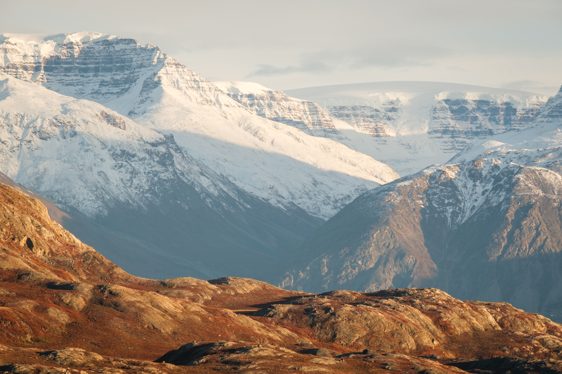 Snow covered mountains behind Red Island in Scoresbysund.