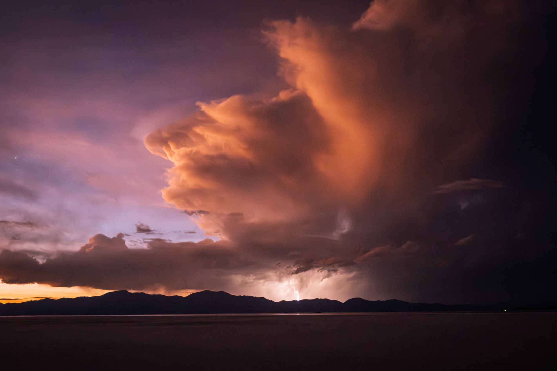 Gewitterstimmung über dem Salzsee mit dramatischen Wolken und Blitz am Horizont.