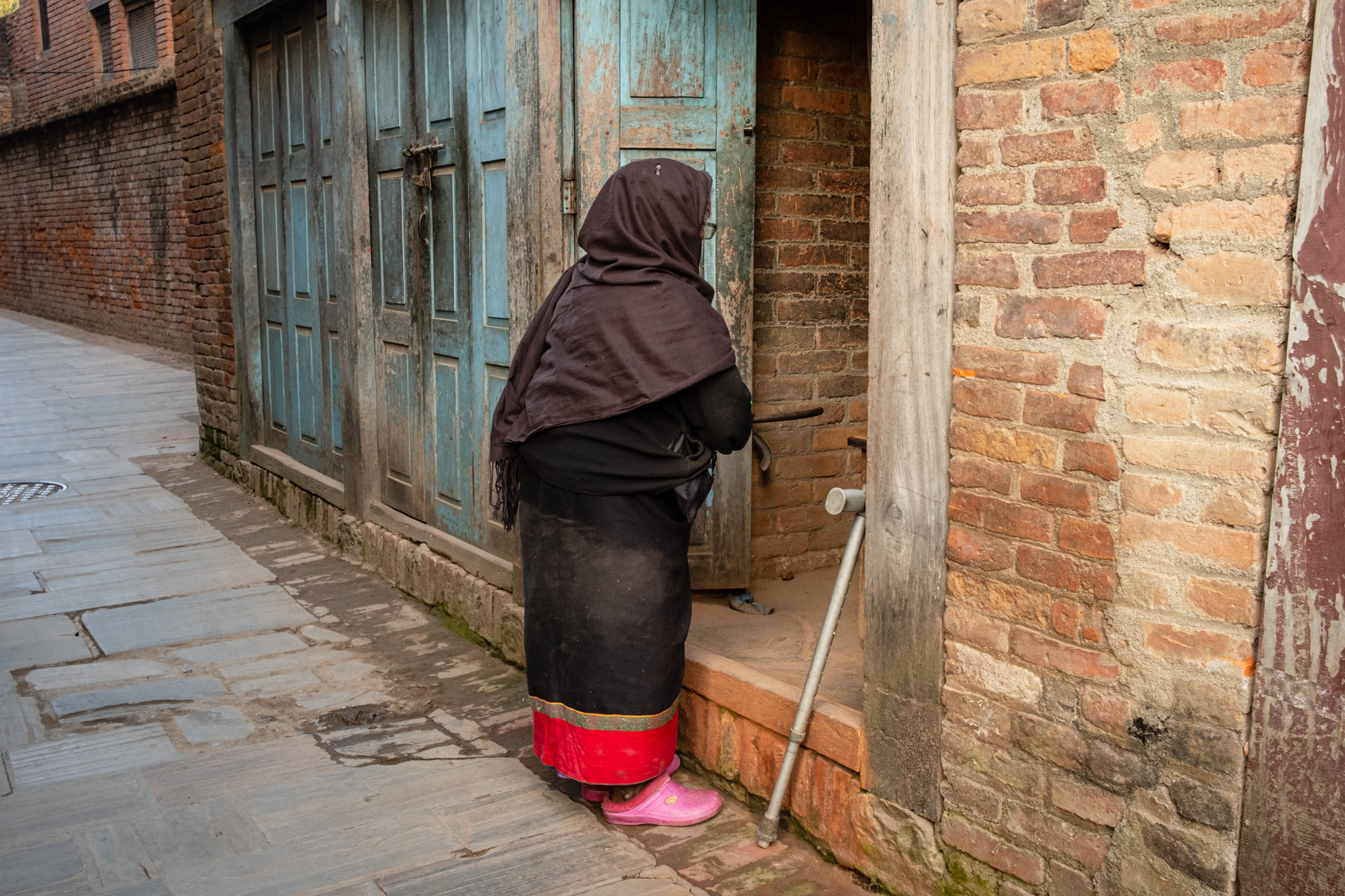 Ältere Dame in einer engen Gassen von Bhaktapurs historischer Altstadt.