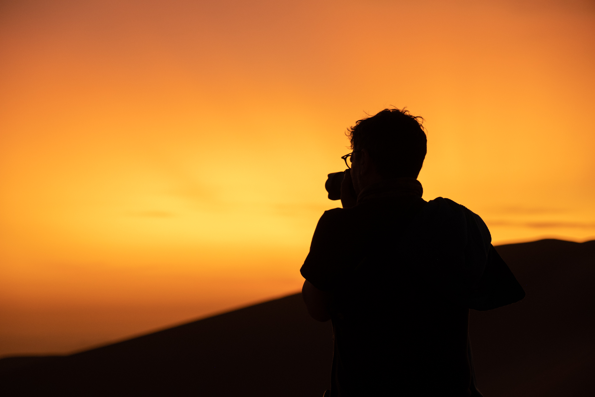 Teilnehmer fotografiert beim Sonnenaufgang auf einer Sanddüne bei Huacachina. 