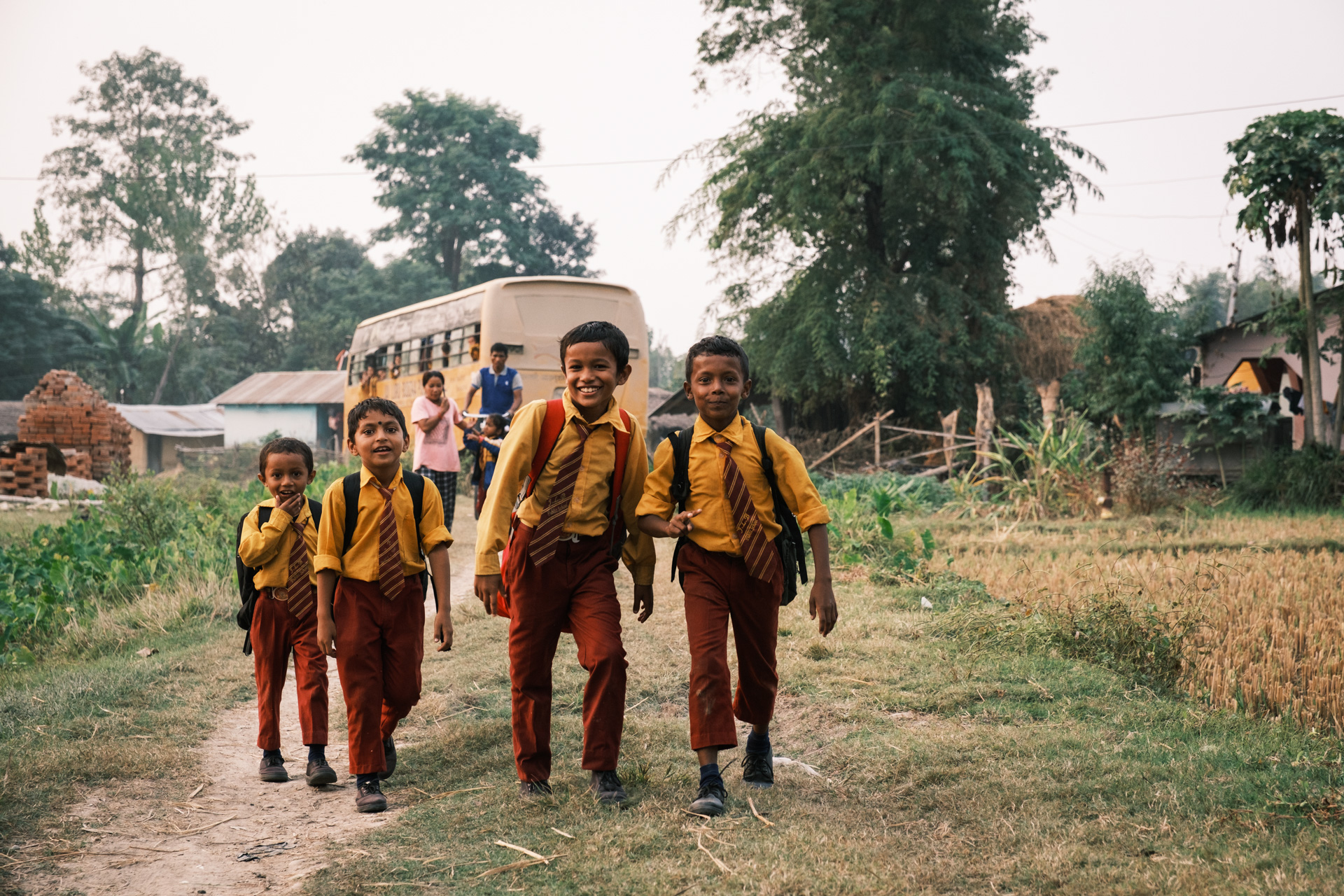 Schulkinder vor Schulbus in der Terai Region Nepals.